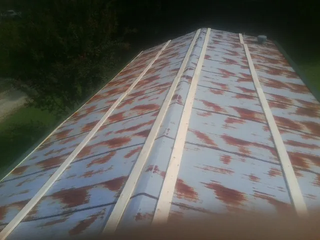 Rusted metal roof panels with new wood purlins before replacement — Storm Damage Roof Repair in Buffalo Center by Roofing Brothers