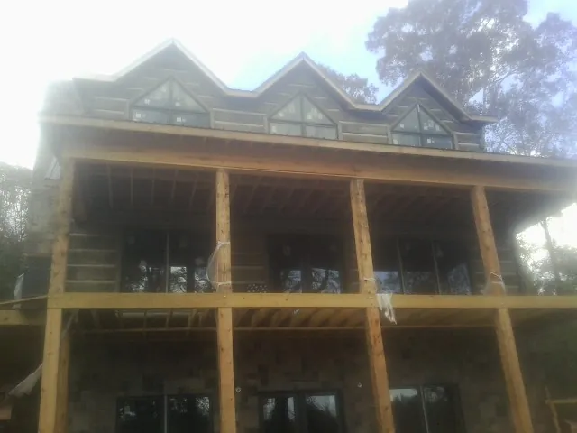 Dormers and porch framing on a large log home under construction — Roof Coating work by our crew in Buffalo Center