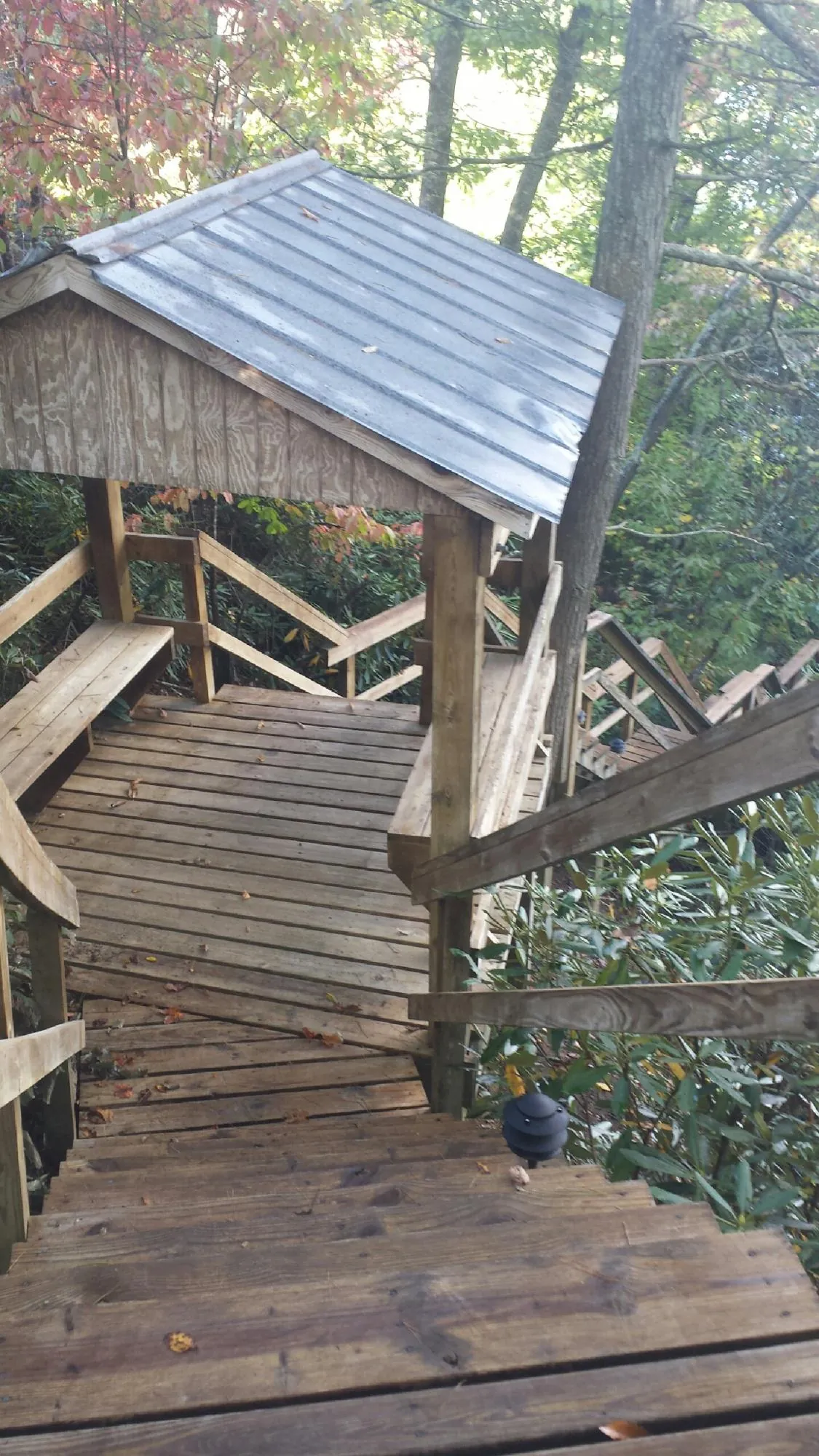 Metal roofed shelter over wooden steps on a wooded walkway — Skylight Repair & Installation work by our crew in Buffalo Center