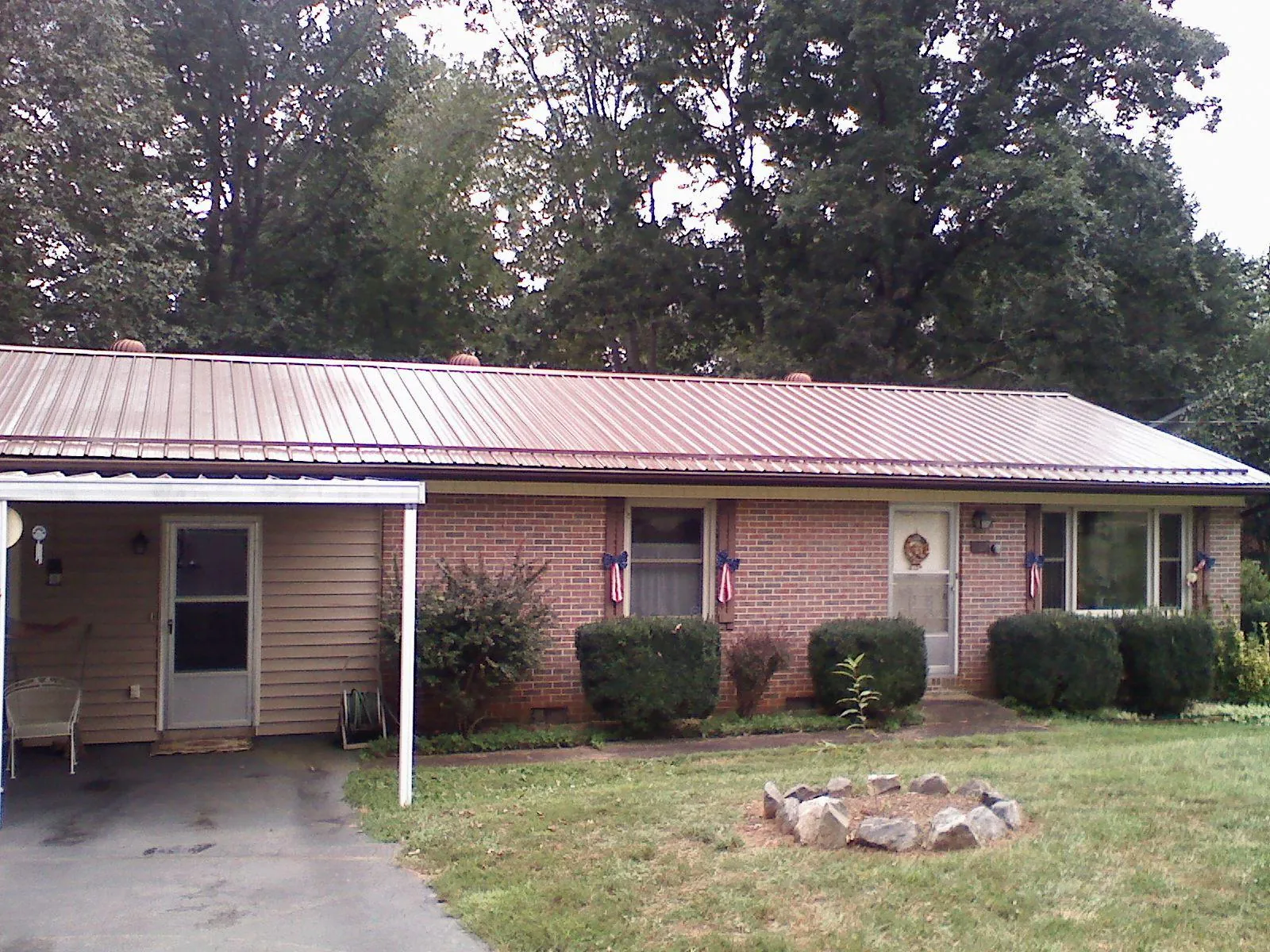 Bronze metal roof and carport on a brick ranch home — Roof Repair work by our crew in Buffalo Center