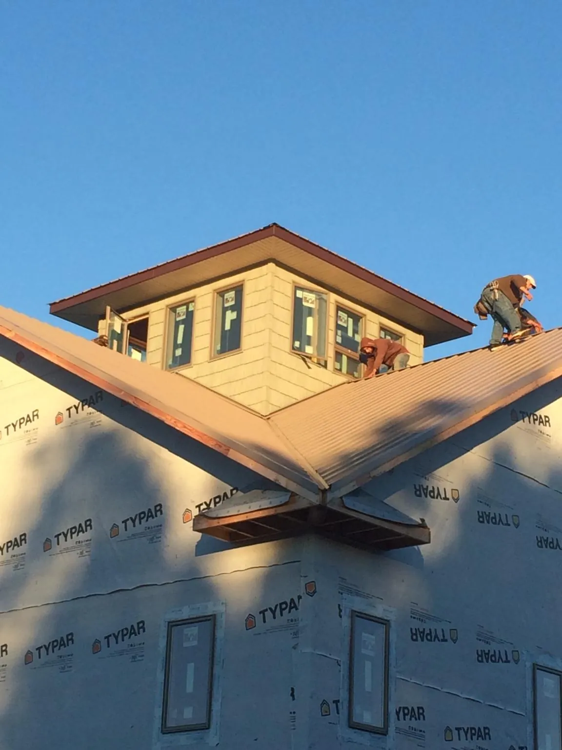 Roofers working around a rooftop cupola on a new metal roof at sunset — Roof Waterproofing in Buffalo Center by Roofing Brothers